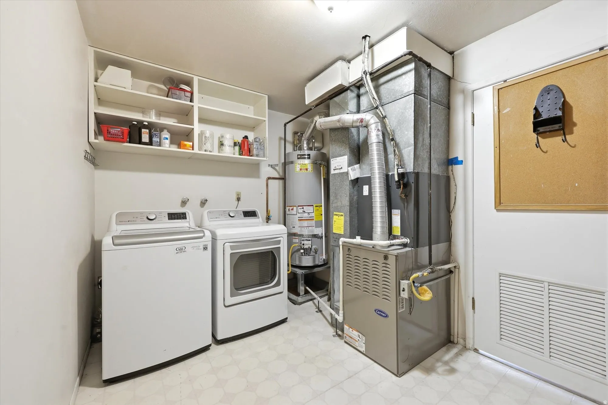 Dedicated laundry area featuring built-in white cabinetry, a white door with a lower vent, and a patterned floor