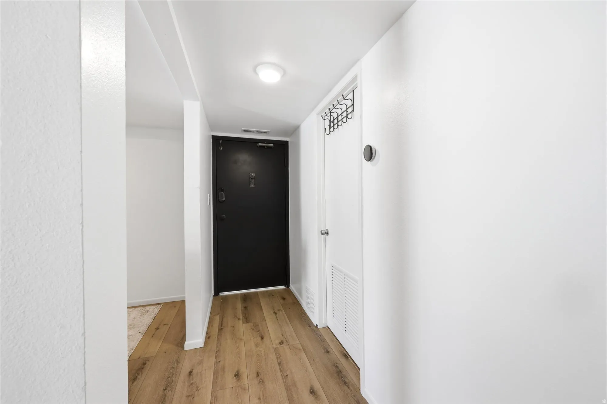 Entryway featuring wood-finish flooring, a contemporary black entry door, and recessed lighting
