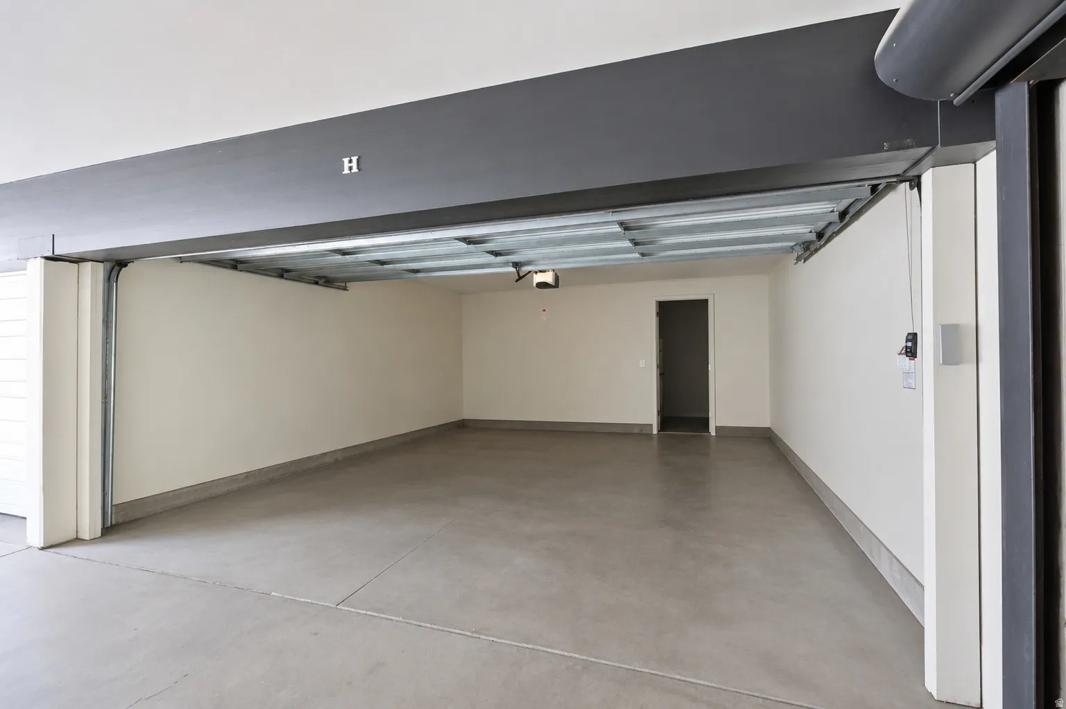 Spacious garage with concrete flooring, painted walls, and an interior access door