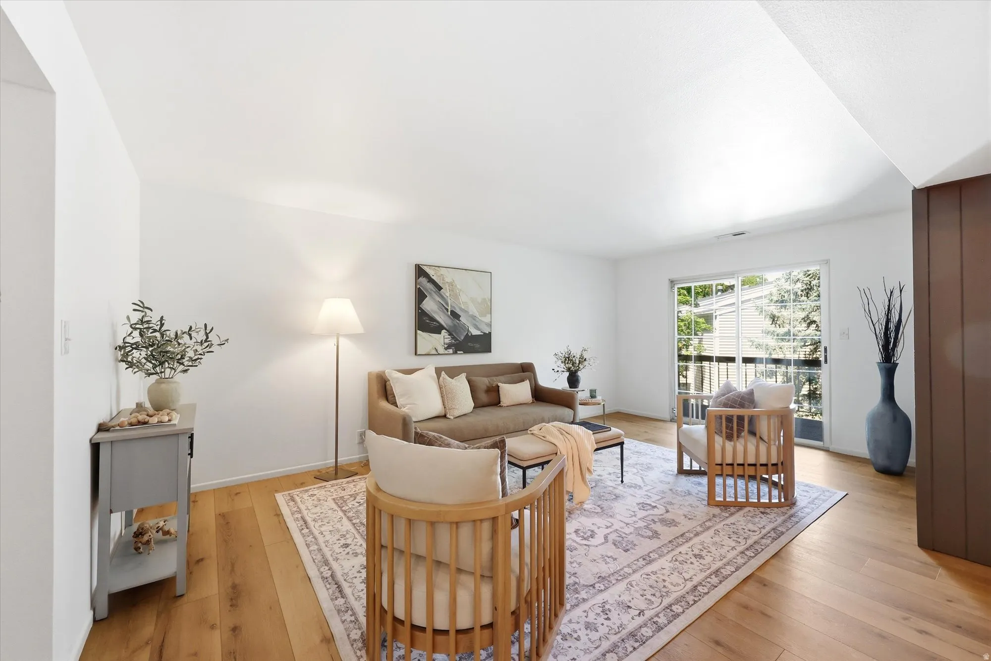 Living area featuring wood-finish flooring, white walls, and a large sliding glass door