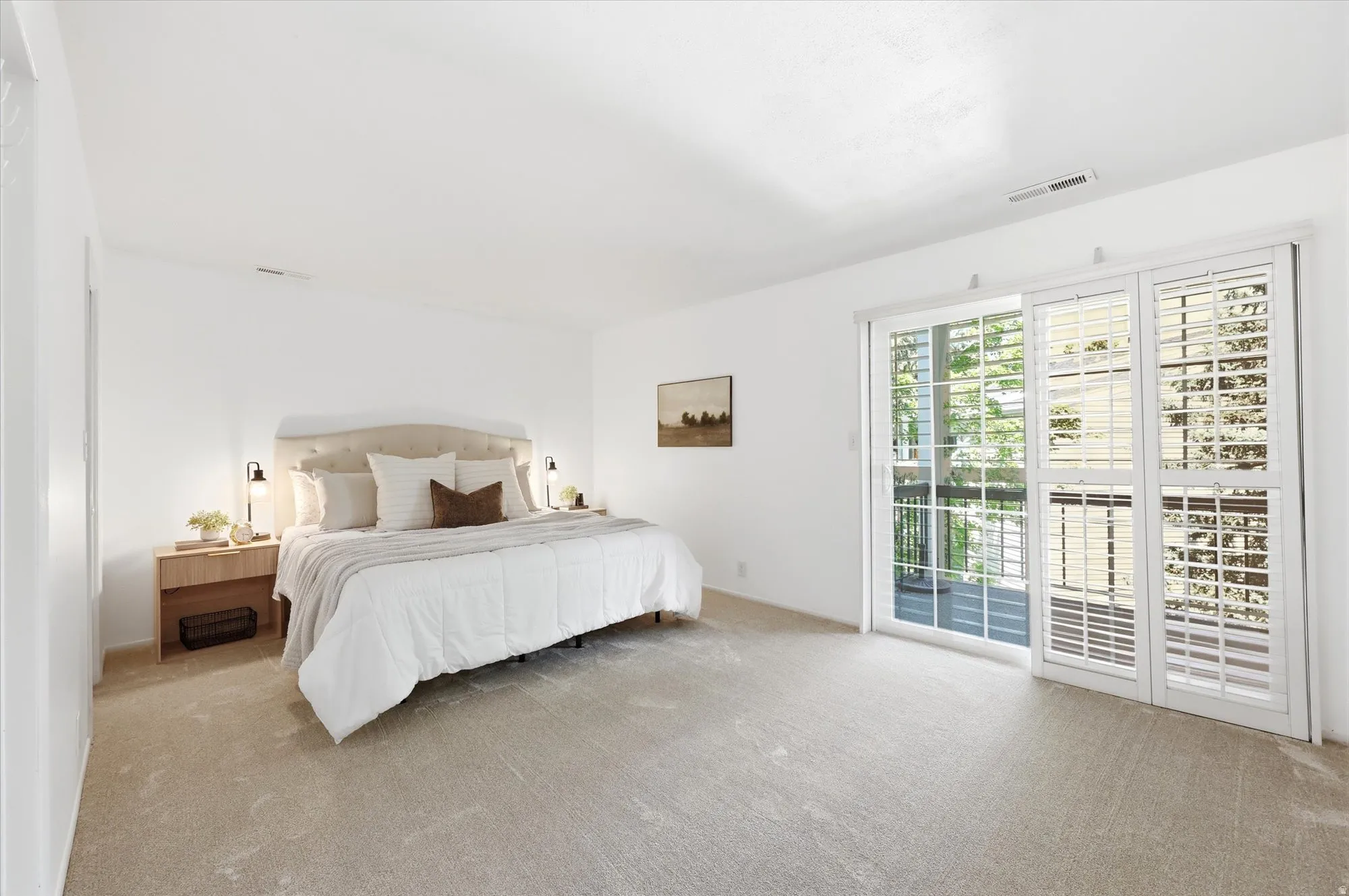 Spacious room featuring light-colored carpeting and a sliding glass door with white plantation shutters