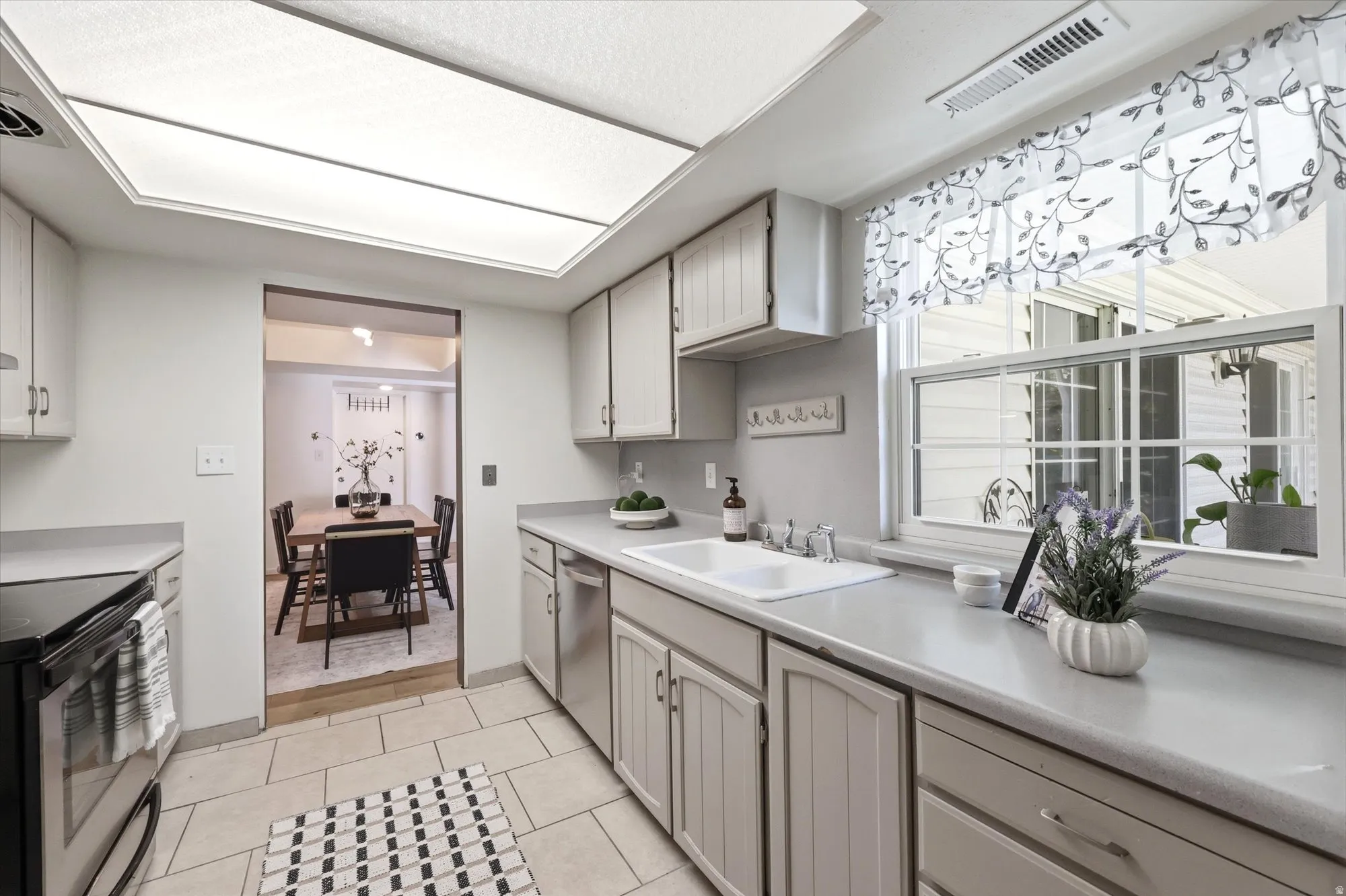 Kitchen featuring light wood-finish cabinetry, a large fluorescent ceiling light, and a window above the sink