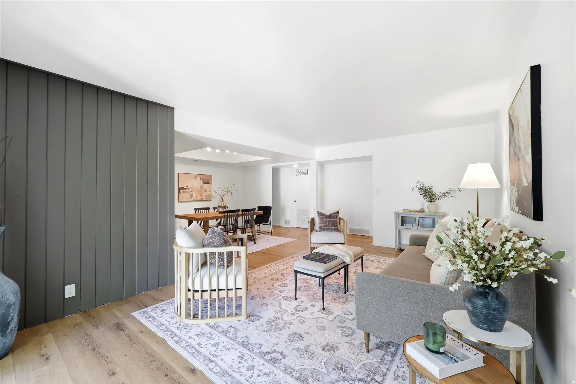 Open-concept living space featuring wood-finish flooring, a neutral color palette, recessed lighting, and a dark accent wall