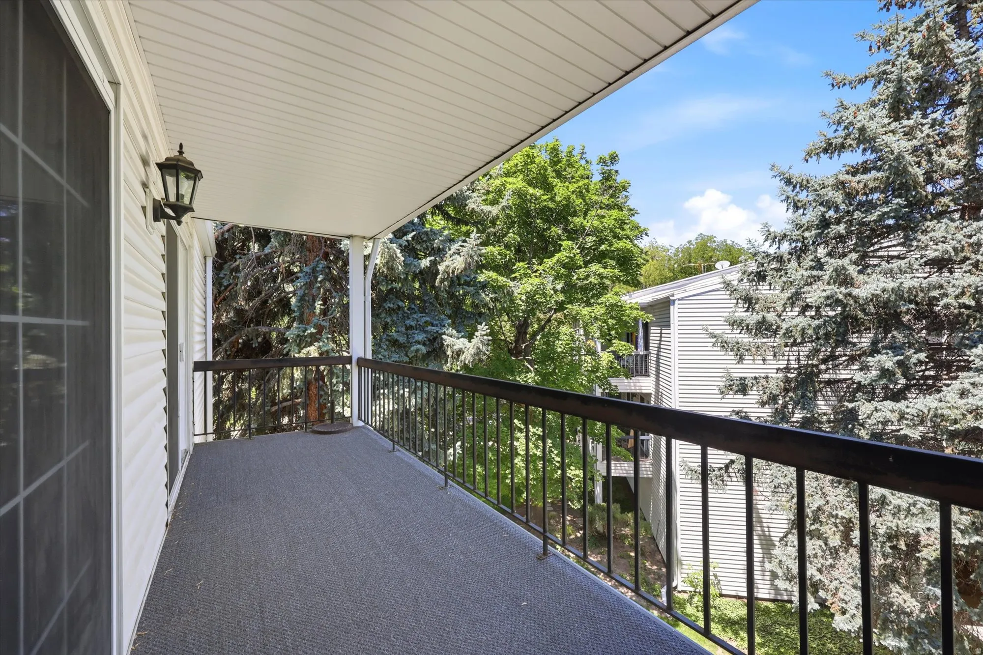 Covered balcony featuring a black metal railing and a textured floor surface