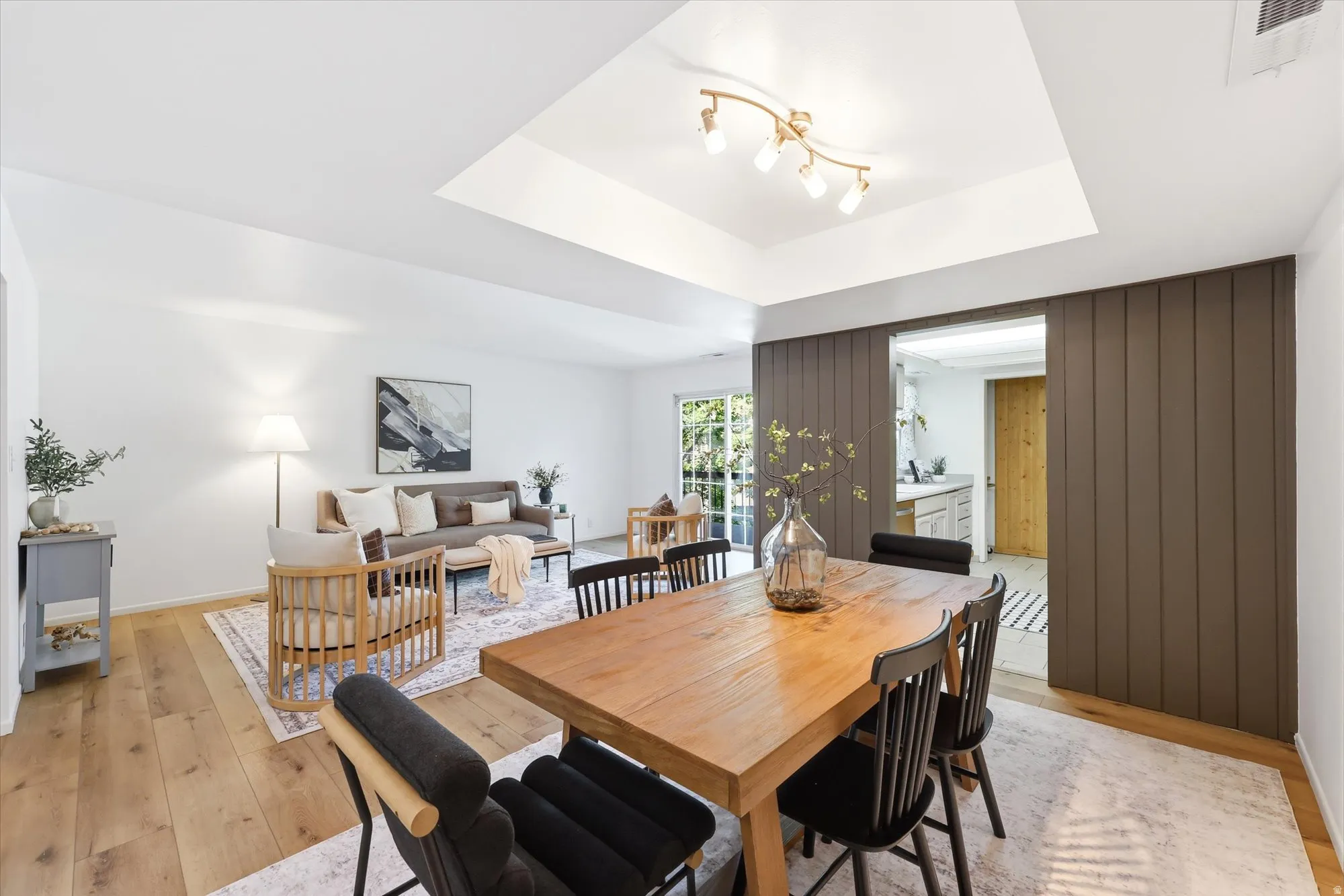 Spacious dining area featuring wood-finish flooring and a tray ceiling with track lighting