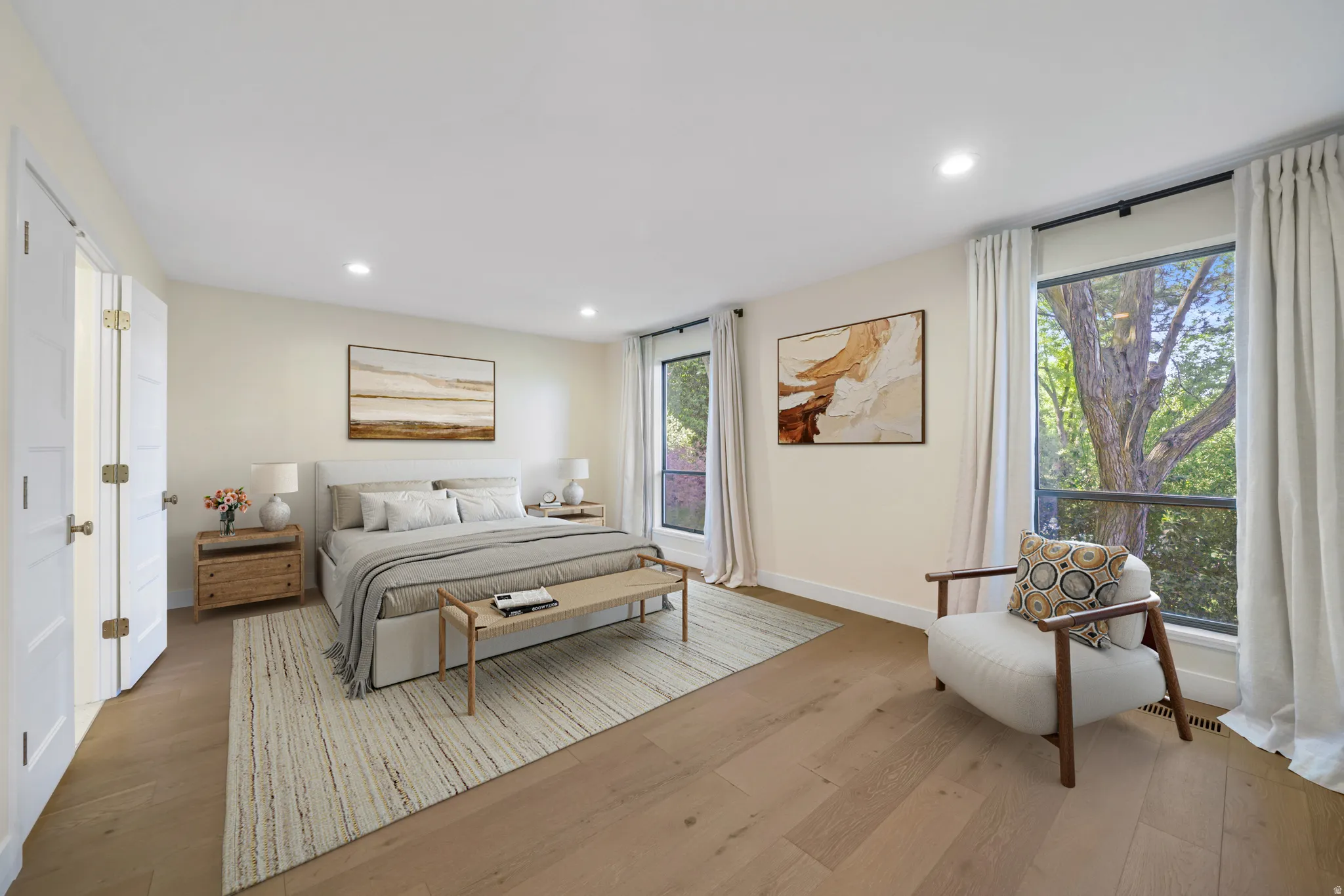 Spacious room featuring wood-finish flooring, recessed lighting, and large windows with privacy drapery