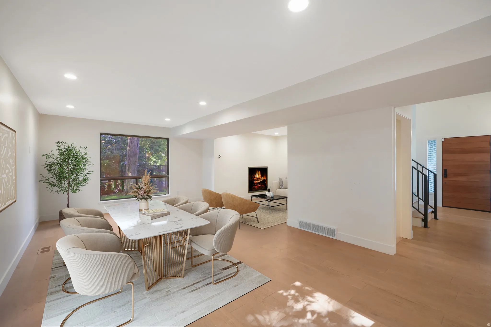 Expansive living area with light wood-finish flooring, recessed lighting, and a large picture window