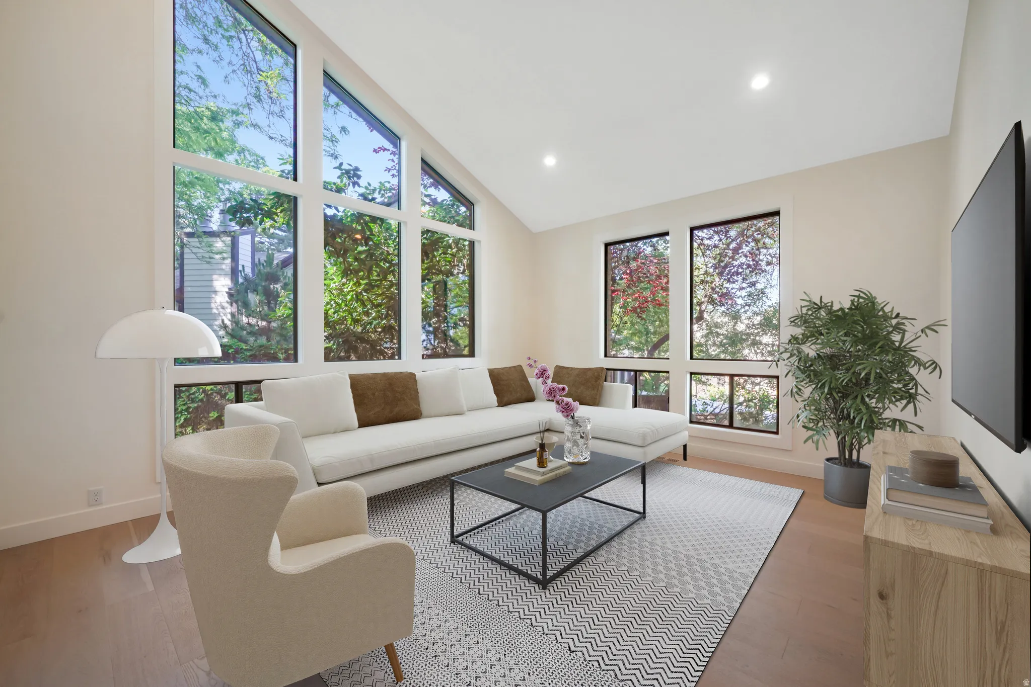 Living space featuring a vaulted ceiling and expansive window array