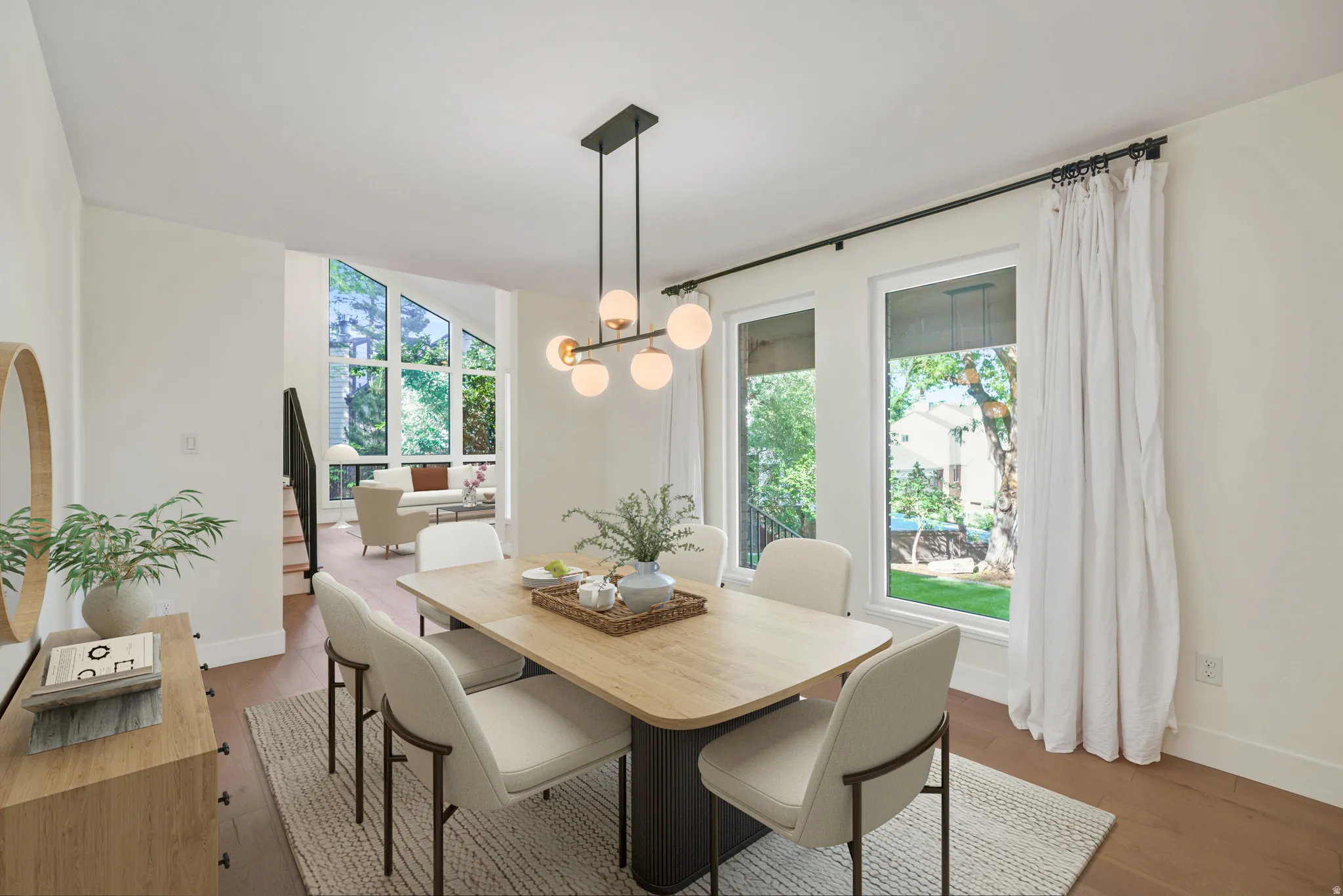 Dining area featuring wood-finish flooring, a contemporary chandelier, and multiple windows providing natural light