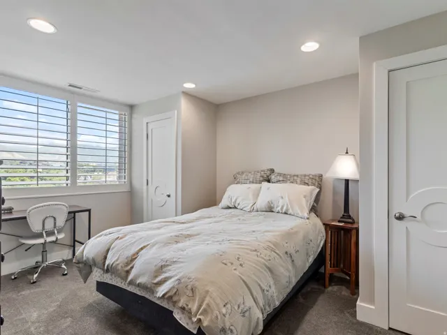 Bedroom featuring a large window with white plantation shutters, offering expansive mountain scenery