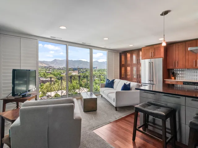 Open-concept living space featuring expansive windows, recessed lighting, wood-finish flooring, a contemporary kitchen with stainless steel appliances, and a balcony with ornate iron-drape railing...like on a wedding cake (thus the nickname for the 'weddi