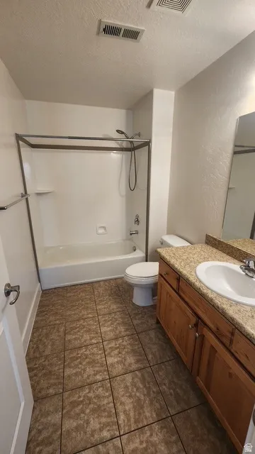 Bathroom featuring a tub/shower combination, tile flooring, and a wood-finish vanity with a light-toned countertop