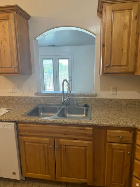 Kitchen sink area with a dual-basin stainless steel sink, gooseneck faucet, and light wood-finish cabinetry