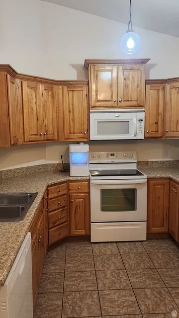 Kitchen featuring warm wood cabinetry, granite-look countertops, and an integrated over-the-range microwave