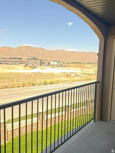 Balcony featuring a black metal railing, concrete flooring, and an arched stucco ceiling