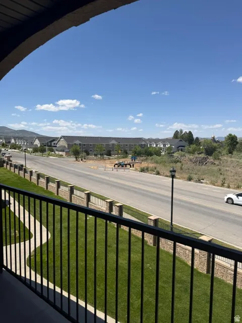 Balcony featuring black metal railing and a curving concrete pathway