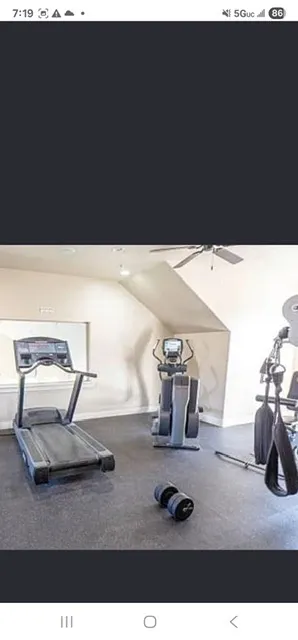 Dedicated fitness area featuring rubber flooring and a ceiling fan