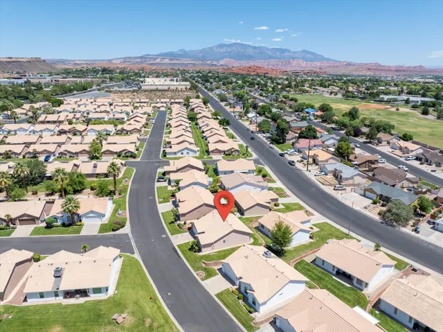 Aerial perspective of a residential community featuring single-story homes with light-colored roofs