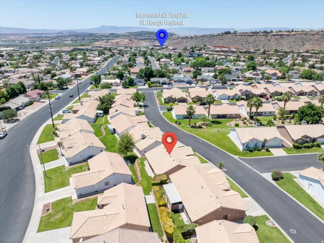 Aerial view showcasing a residential neighborhood with single-story homes, paved streets, and green lawns