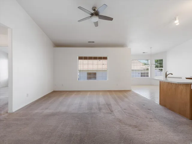 Spacious interior with neutral carpeting and a ceiling fan