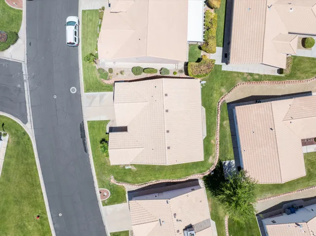 Overhead residential property featuring a tan tile roof, green lawn, and concrete driveway