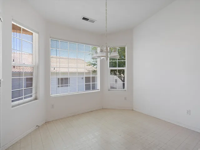 Dining area featuring bay windows, white window blinds, a white chandelier, and light-toned flooring