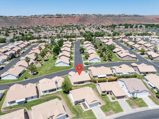 Aerial view of a residential community featuring single-story properties with tan roofs and light-colored exteriors