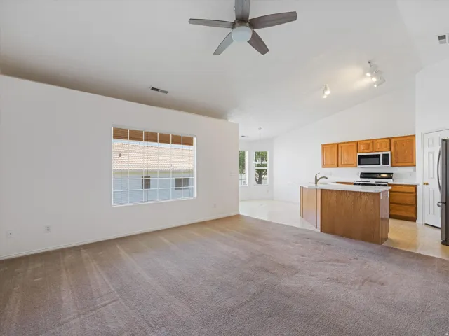 Open-concept living space featuring a vaulted ceiling and a ceiling fan