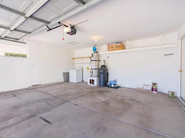Spacious garage featuring a concrete floor, overhead garage door with opener, and a single window