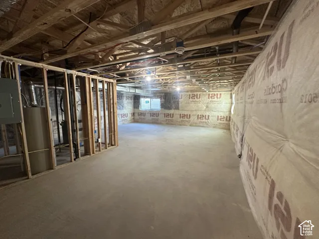 Unfinished basement with concrete flooring, framed wall partitions, exposed ceiling joists, and visible insulation