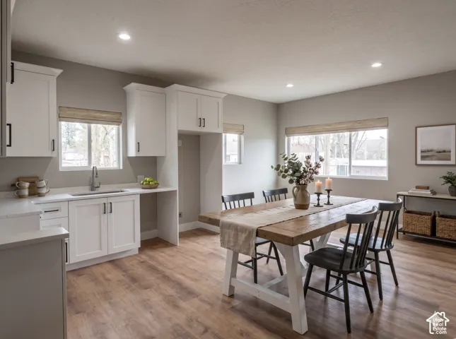 Open-concept kitchen and dining area featuring wood-finish flooring, white cabinetry, recessed lighting, and ample natural light from multiple windows  Virtually Staged to give you an idea of space planning