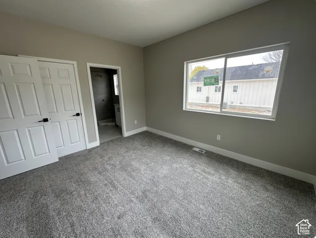 Neutral-toned bedroom featuring new gray carpet, white trim, and a large window