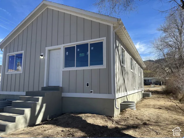 Newly constructed residence featuring vertical panel siding, white trim, and a prominent front entry with concrete steps