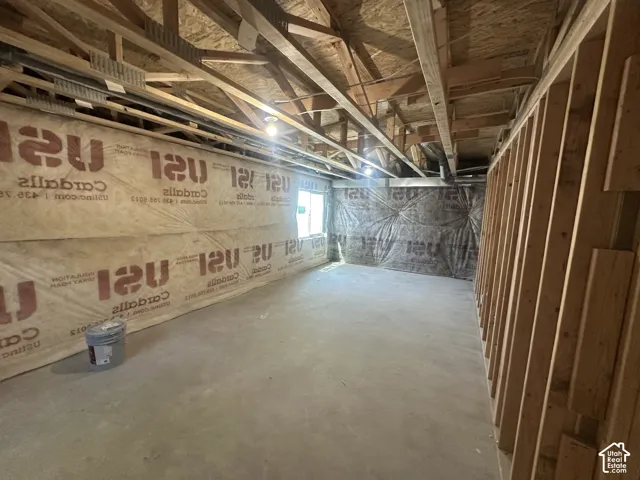 Unfinished basement offering exposed ceiling joists, wood framing, a concrete floor, and insulated walls