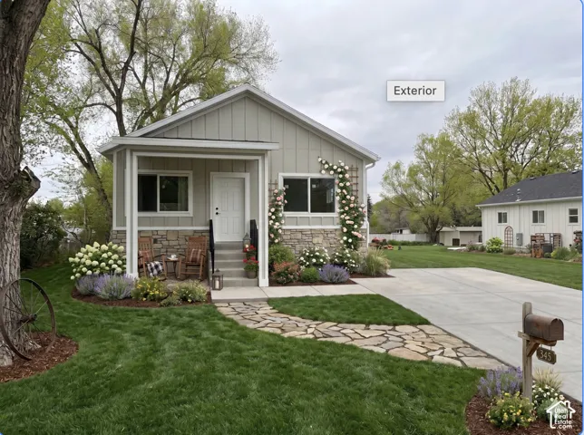 Charming front exterior  Virtually Staged to give you an idea of space planning featuring a covered porch with stone detailing, board and batten siding, and an inviting stone pathway