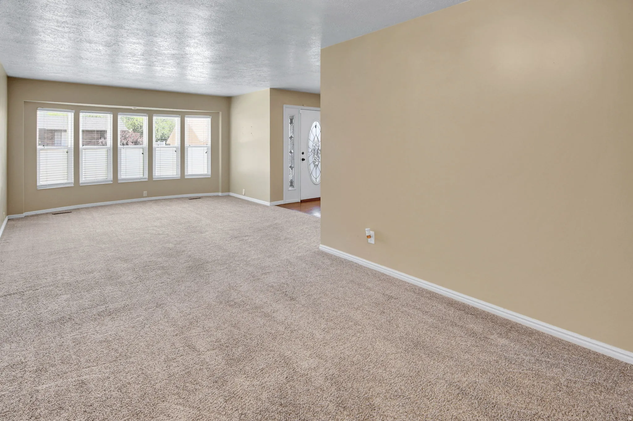 Spacious living area featuring neutral carpeting and light beige wall paint