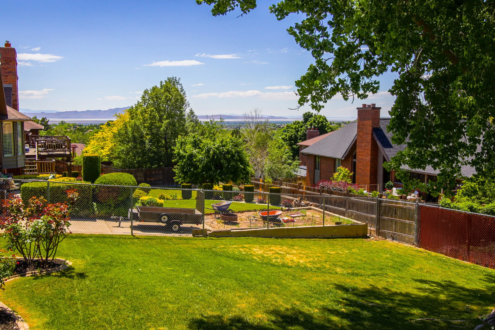 Expansive backyard featuring a lush lawn, established landscaping, and terraced garden beds