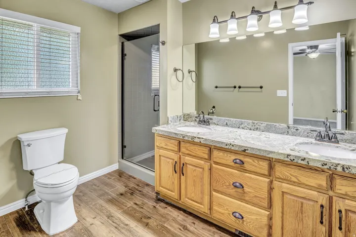 Double vanity with a speckled countertop, integrated sinks, and wood-finish cabinetry