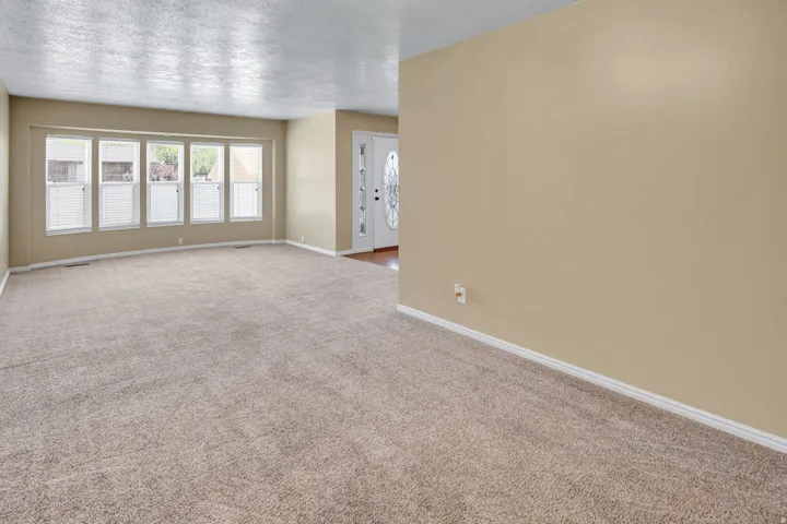 Spacious living area featuring neutral carpeting and light beige wall paint