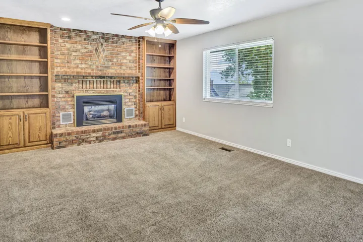 Brick fireplace with hearth, flanked by built-in wood cabinetry and shelving