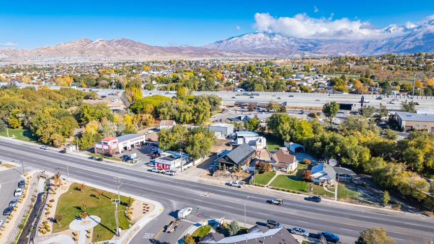 Aerial perspective featuring a main thoroughfare, dense tree cover, and distant snow-capped mountains