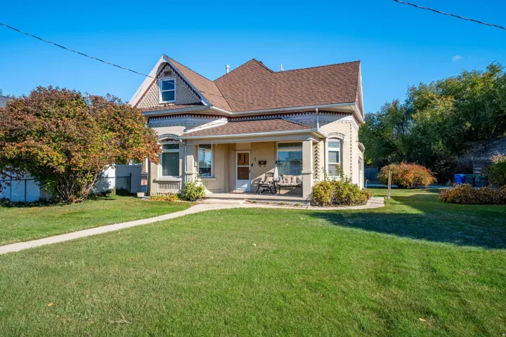 Traditional architecture featuring a covered front porch, gabled roofline, decorative trim, and a manicured lawn