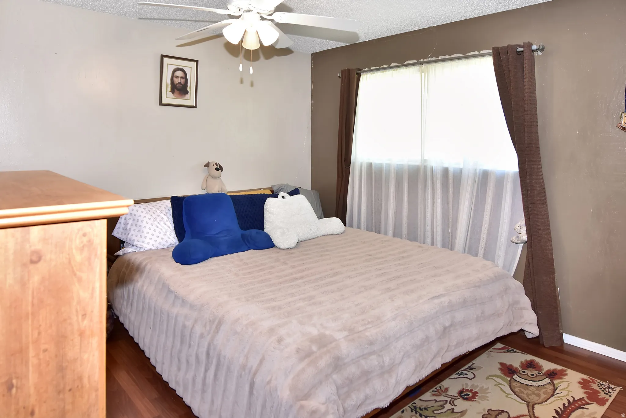 Bedroom featuring wood-finish flooring, a ceiling fan, and a window with curtain rods