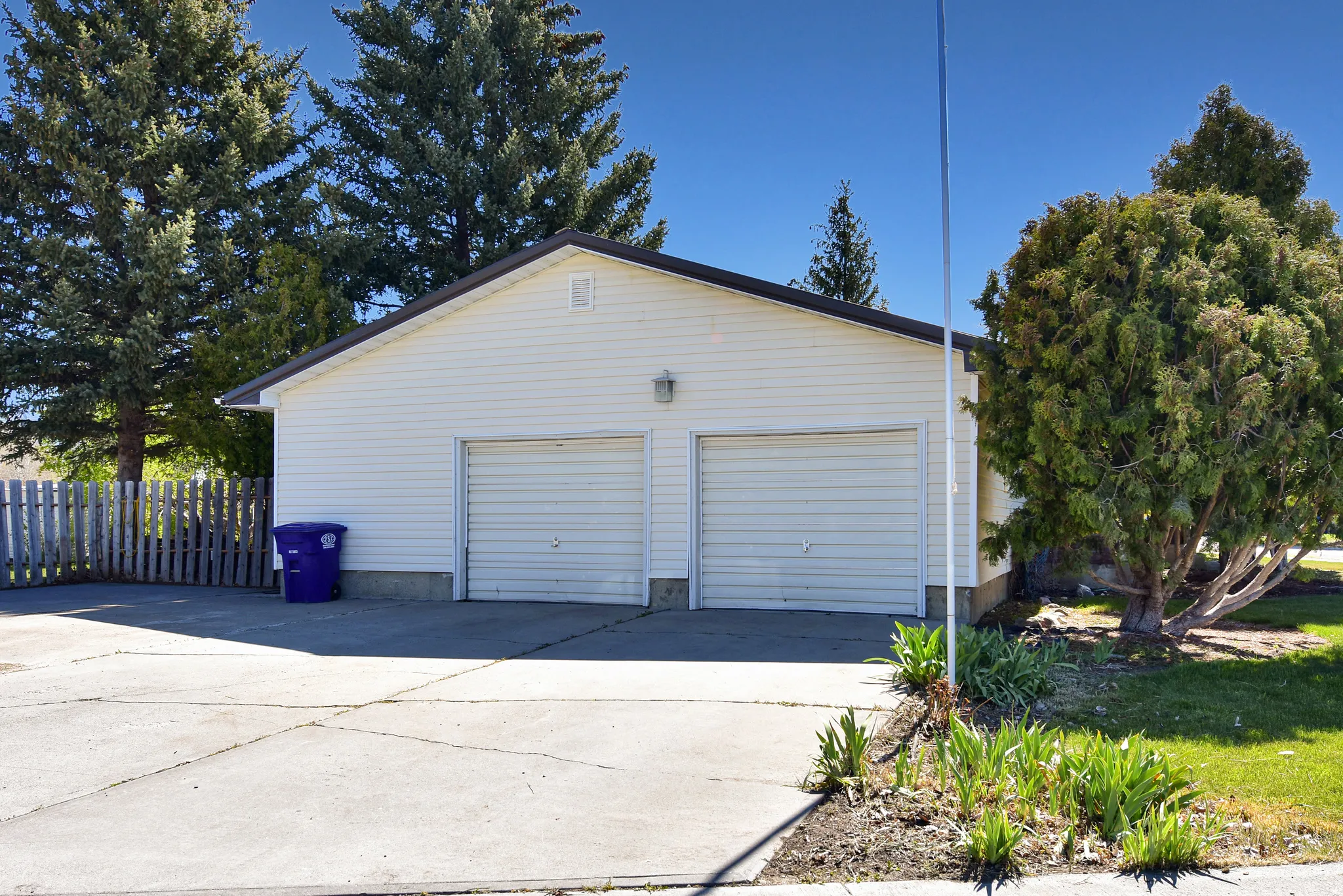 Two-car detached garage with white siding, twin garage doors, and a concrete driveway