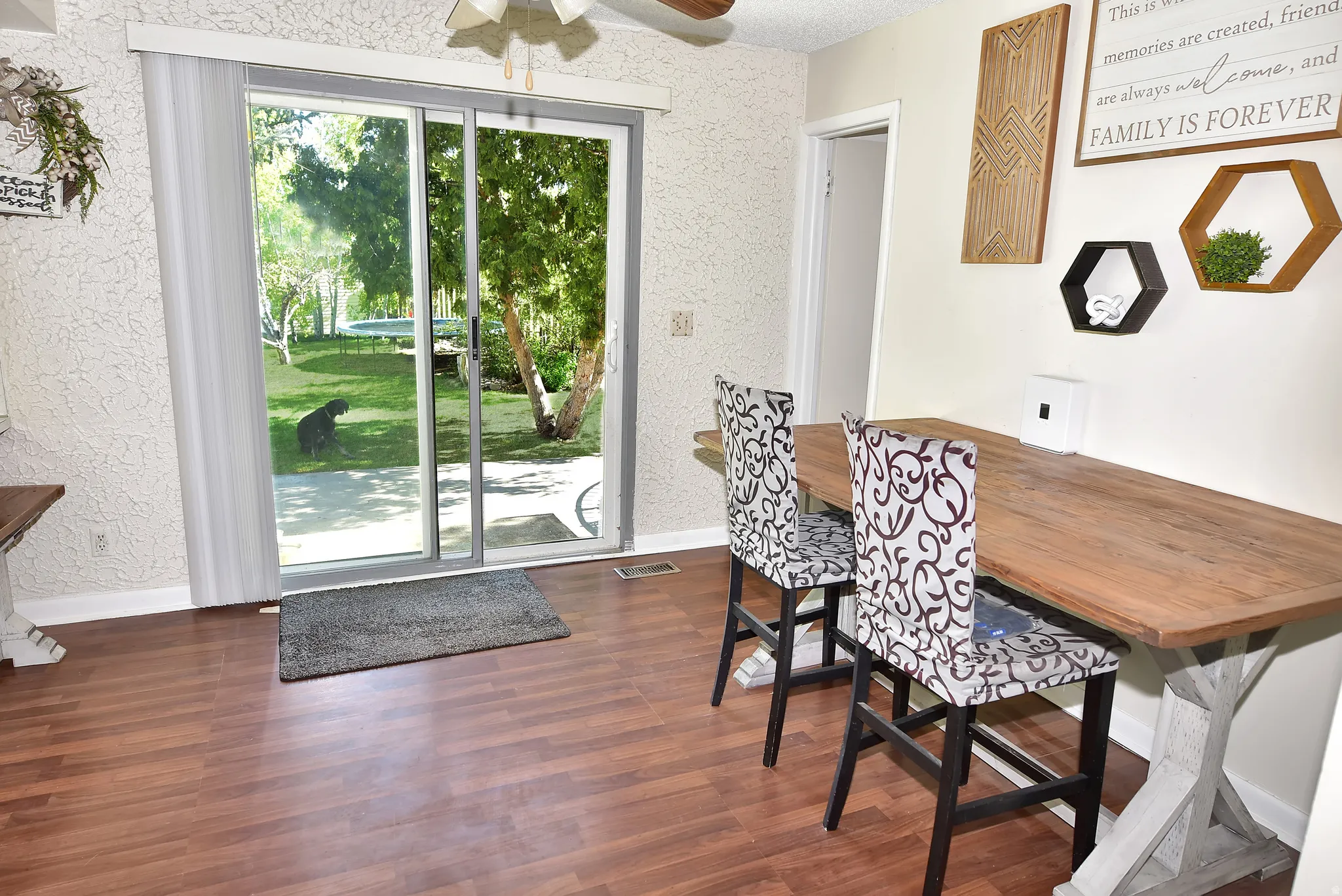 Sliding glass door opening to a private exterior space with mature trees