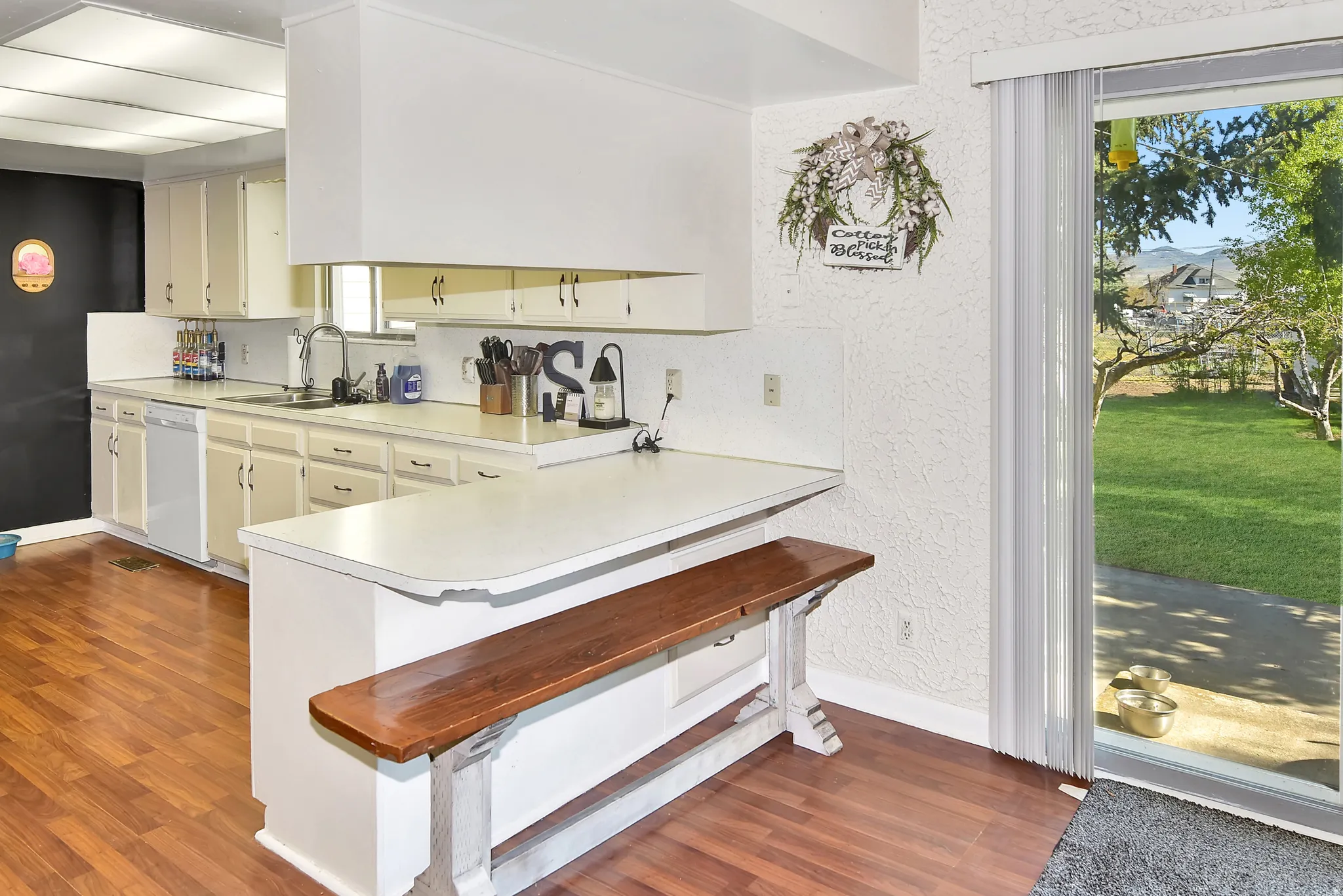 Kitchen featuring wood-finish flooring, white cabinetry, a built-in breakfast bar, and a sliding glass door providing access to the exterior