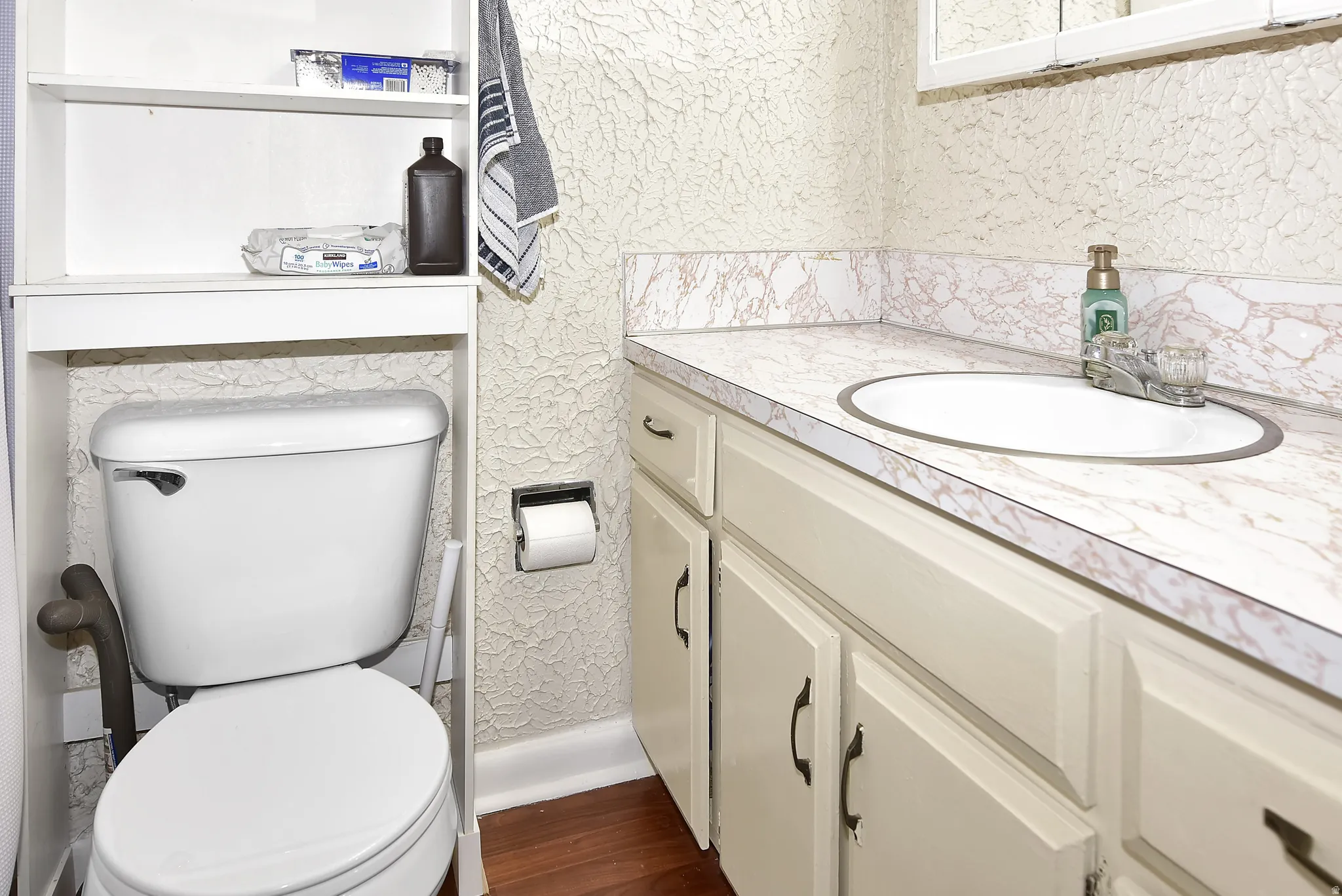 Bathroom vanity with an integrated sink, off-white cabinetry, and a patterned countertop