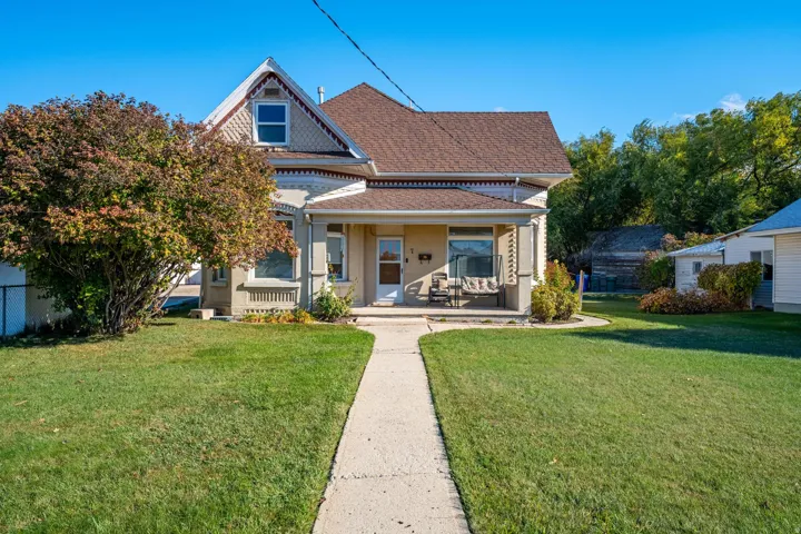 Traditional two-story residence featuring a covered front porch, a gabled roofline with decorative shingles, and a paved walkway leading to the entrance