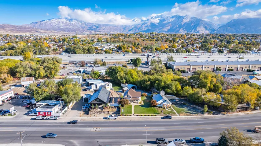 Expansive aerial perspective showcasing a residential property with a manicured lawn, mature trees, and a distant mountain range