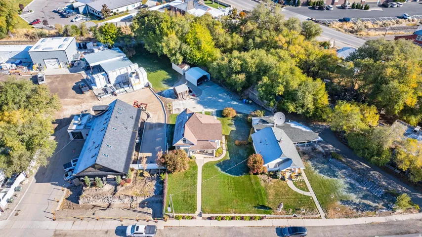 Aerial perspective showcasing two residential properties with manicured front lawns, mature trees, and surrounding commercial structures
